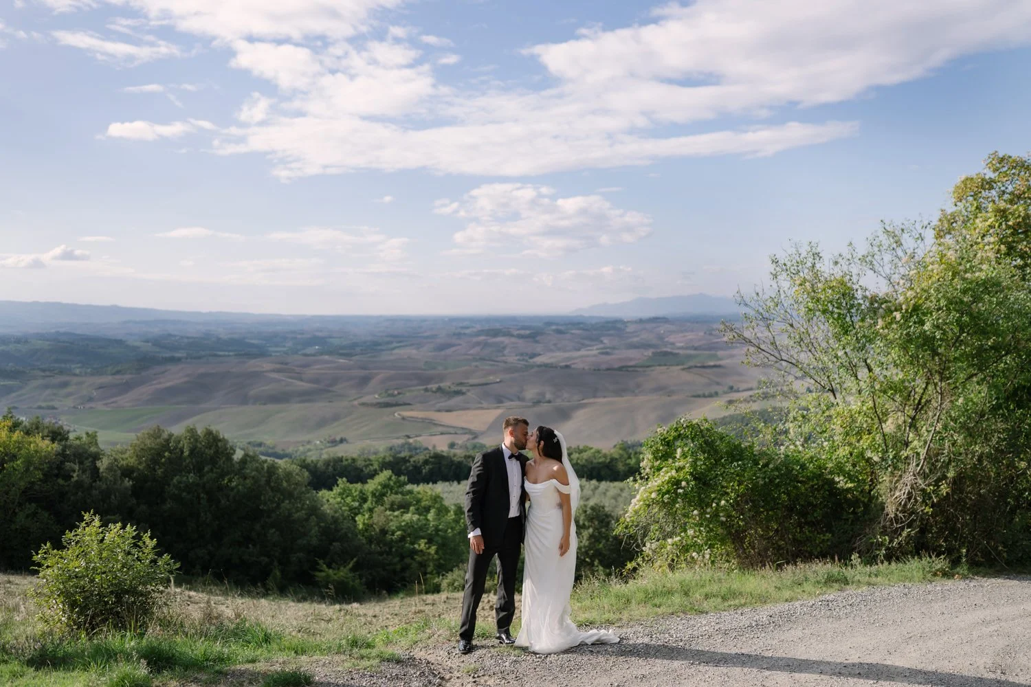 Bride and groom kissing on the path overlooking the Tuscan countryside at Villa di Ulignano, by FunkyBird