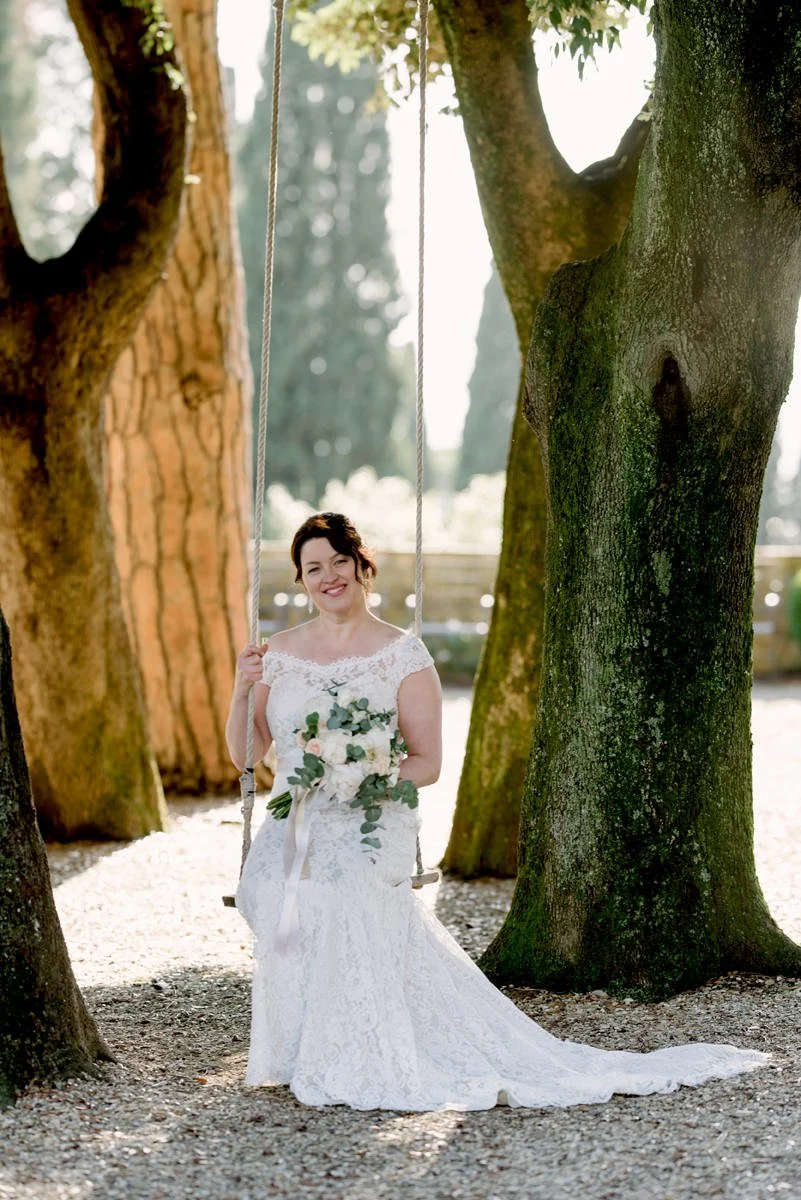 Bride on a garden swing holding her bouquet at Villa Le Fontanelle wedding venue in Florence.