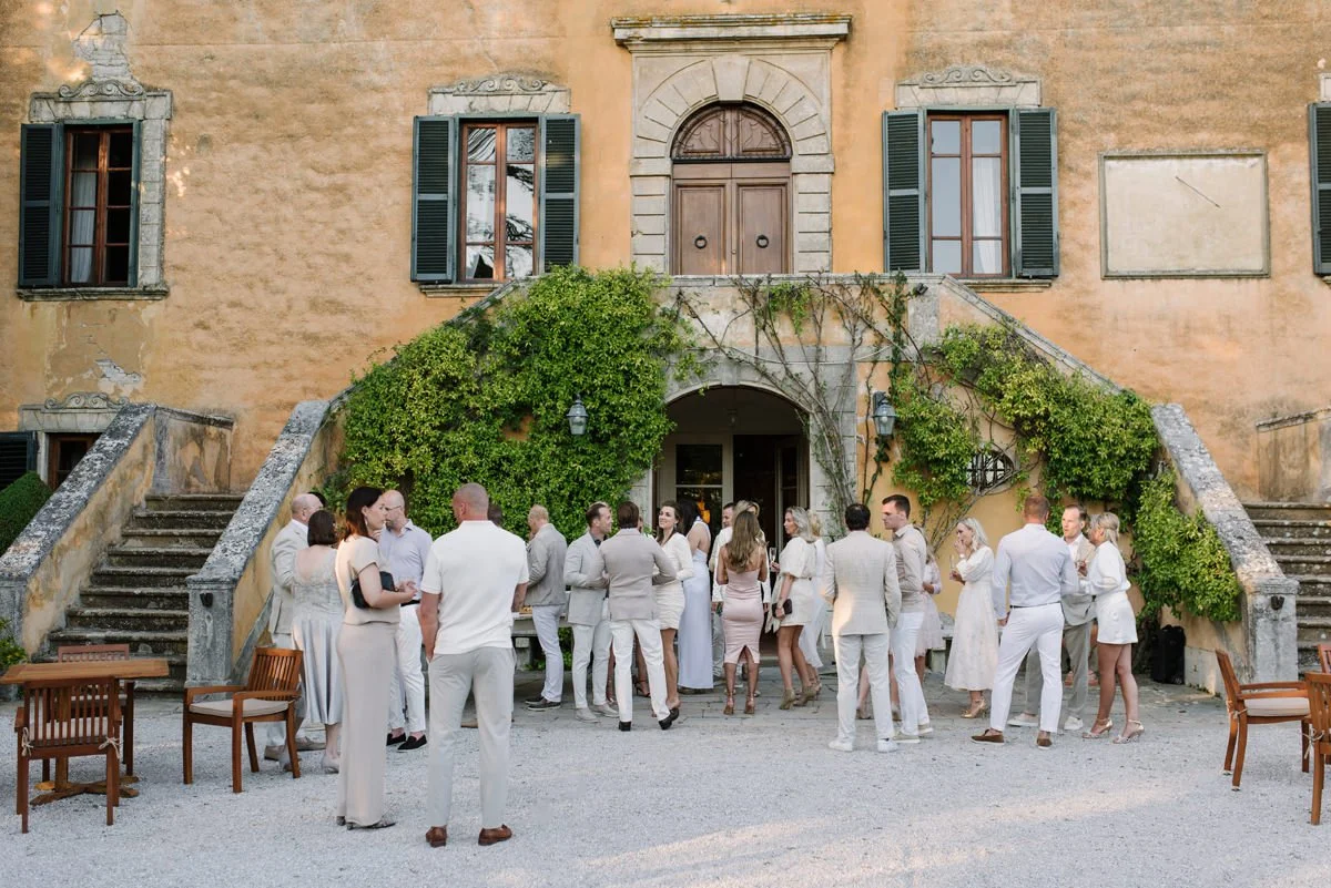 Welcome dinner at Villa di Ulignano set in front of the villa, with guests dressed in white for an outdoor evening gathering.