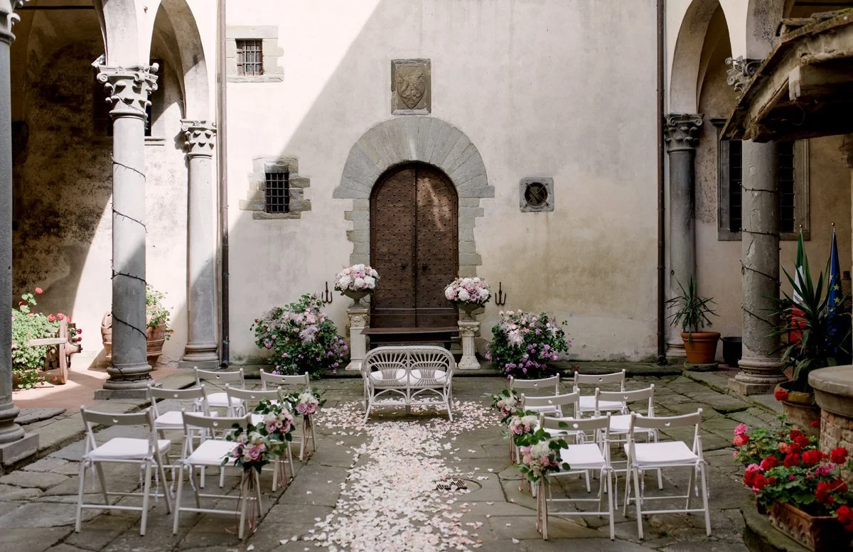 Wedding ceremony inside the historic stone courtyard of Castello del Trebbio in Tuscany.