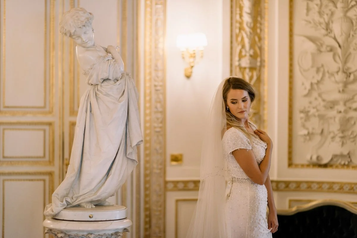 Bride posing beside a classical statue inside Villa Cora, echoing the villa’s historic interiors.