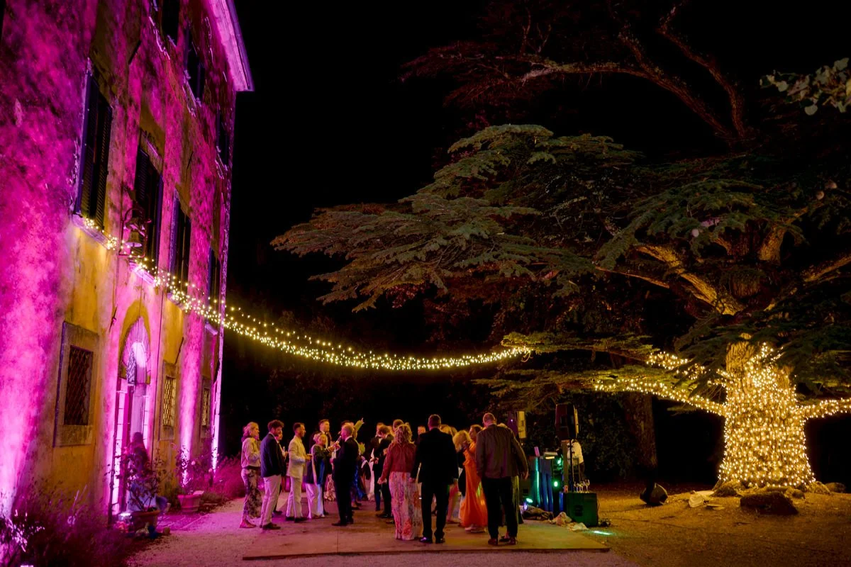 Evening wedding party at the back garden of Villa di Ulignano, set under string lights around the large tree.