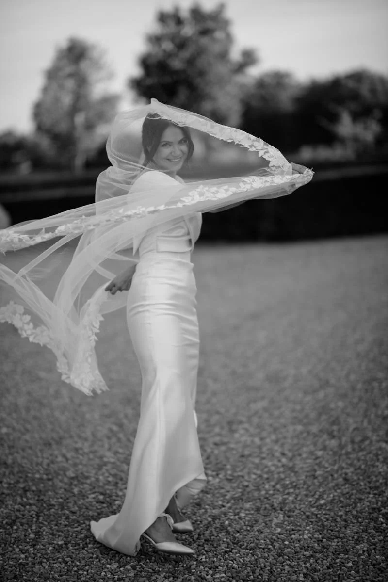 Black and white portrait of the bride smiling and playing with her veil during preparations at Villa Boscarello.