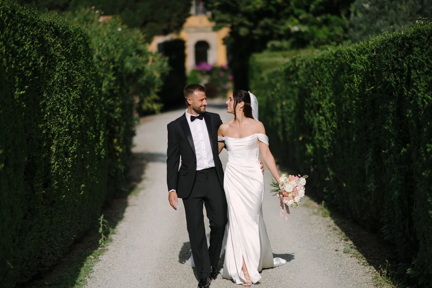 Bride and groom walking through the cypress hedge garden during golden hour at Villa di Ulignano, by FunkyBird