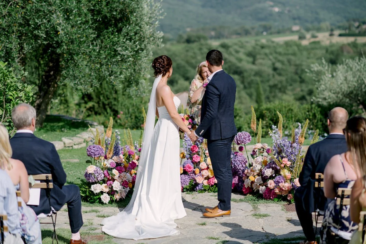 bride and groom at the ceremony rich with flowers at Tuscany wedding at Casa Cornacchi wedding venue