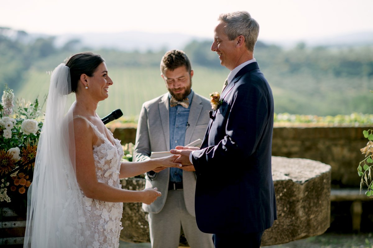 Wedding ceremony at Castello di Bossi with the couple holding hands on the terrace, overlooking the Chianti vineyards in Tuscany.
