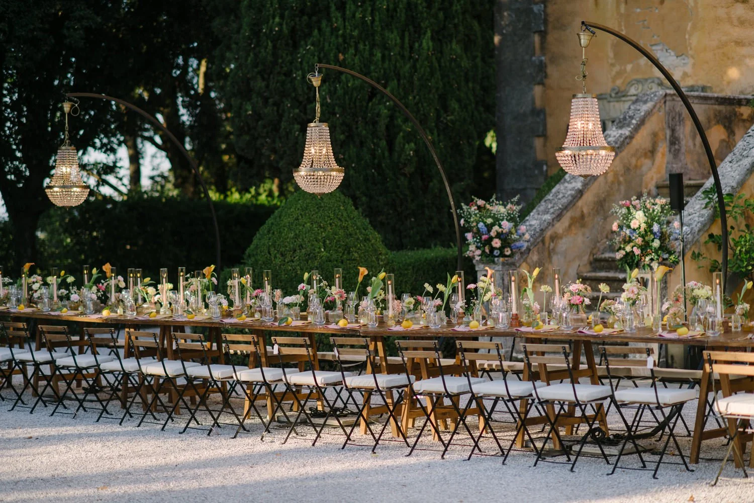 Long-table wedding dinner in front of Villa di Ulignano with six crystal chandeliers above, October wedding by FunkyBird