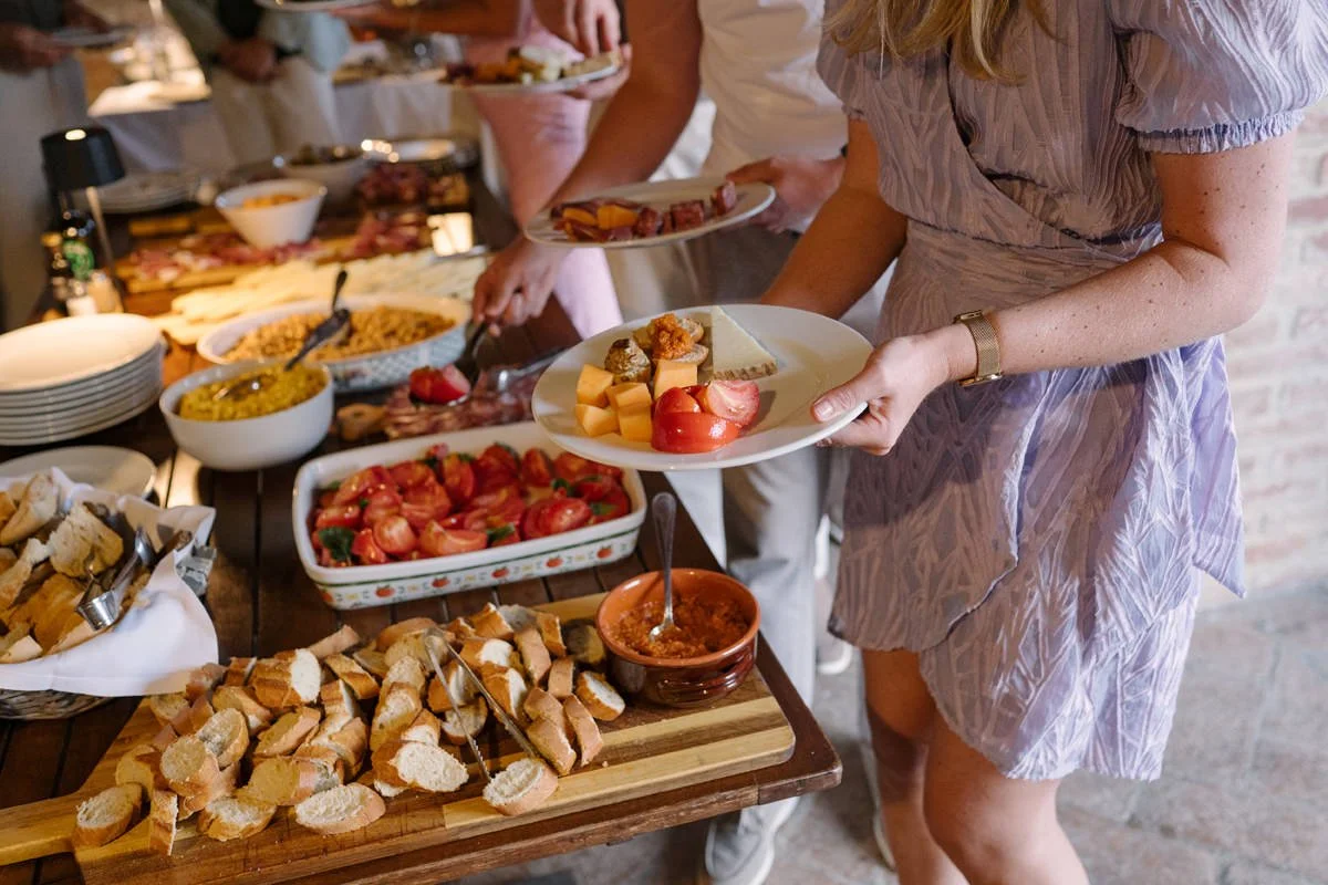 Wedding guests serving food onto their plates during the welcome dinner at Villa Boscarello.