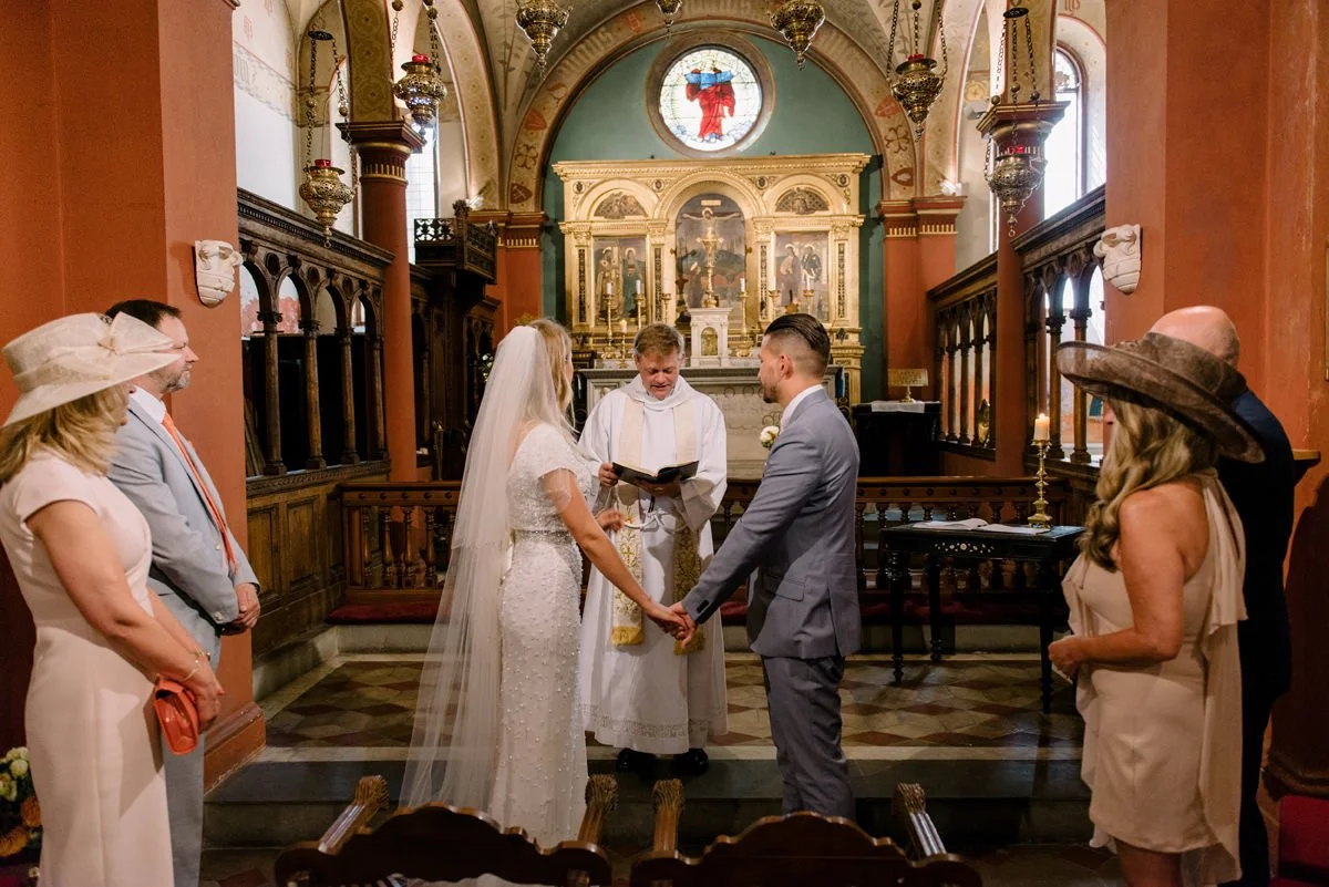 Wedding ceremony in a small English church near Villa Cora, with the couple standing and holding hands.