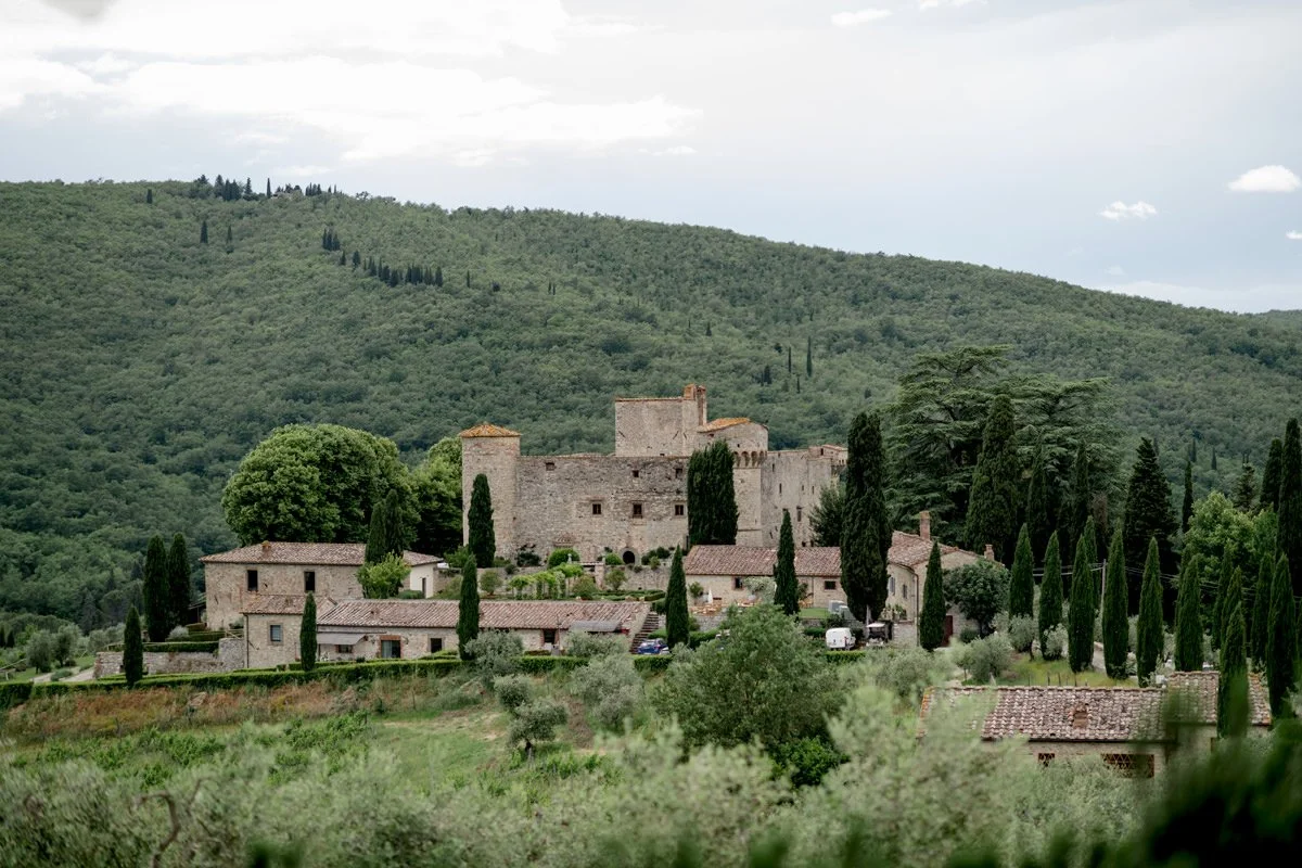 Castello di Meleto wedding venue viewed from a distance, with the historic castle set among rolling Chianti hills in Tuscany.