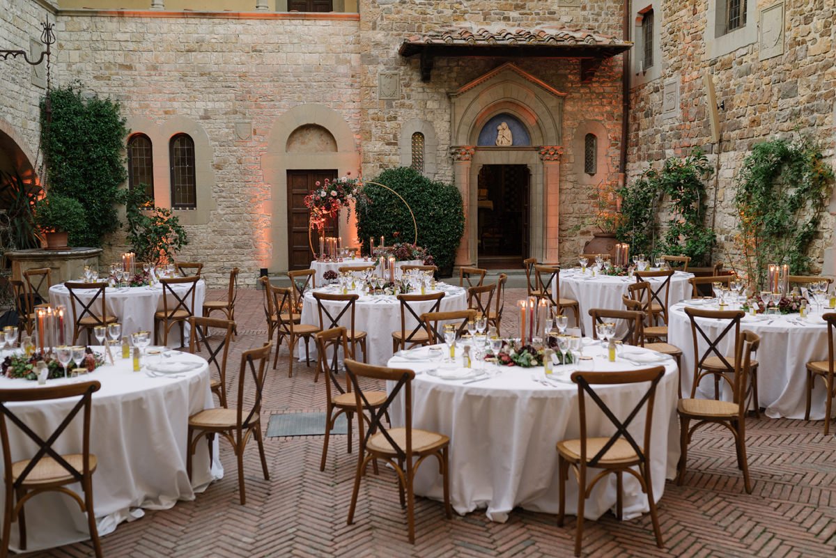 Wedding dinner setup in the courtyard of Castello Il Palagio with decorated tables before guests arrive.