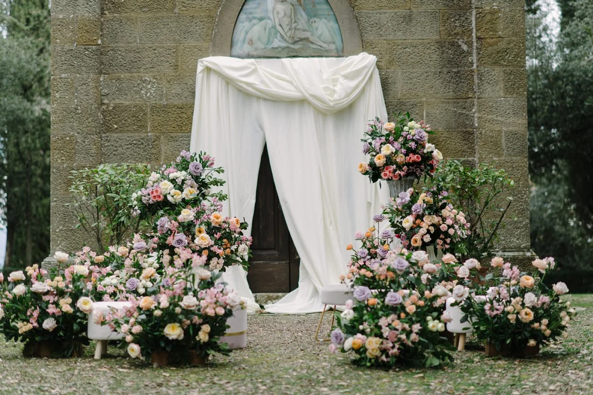 Wedding ceremony in front of the small church at Le Filigare with a large floral installation.