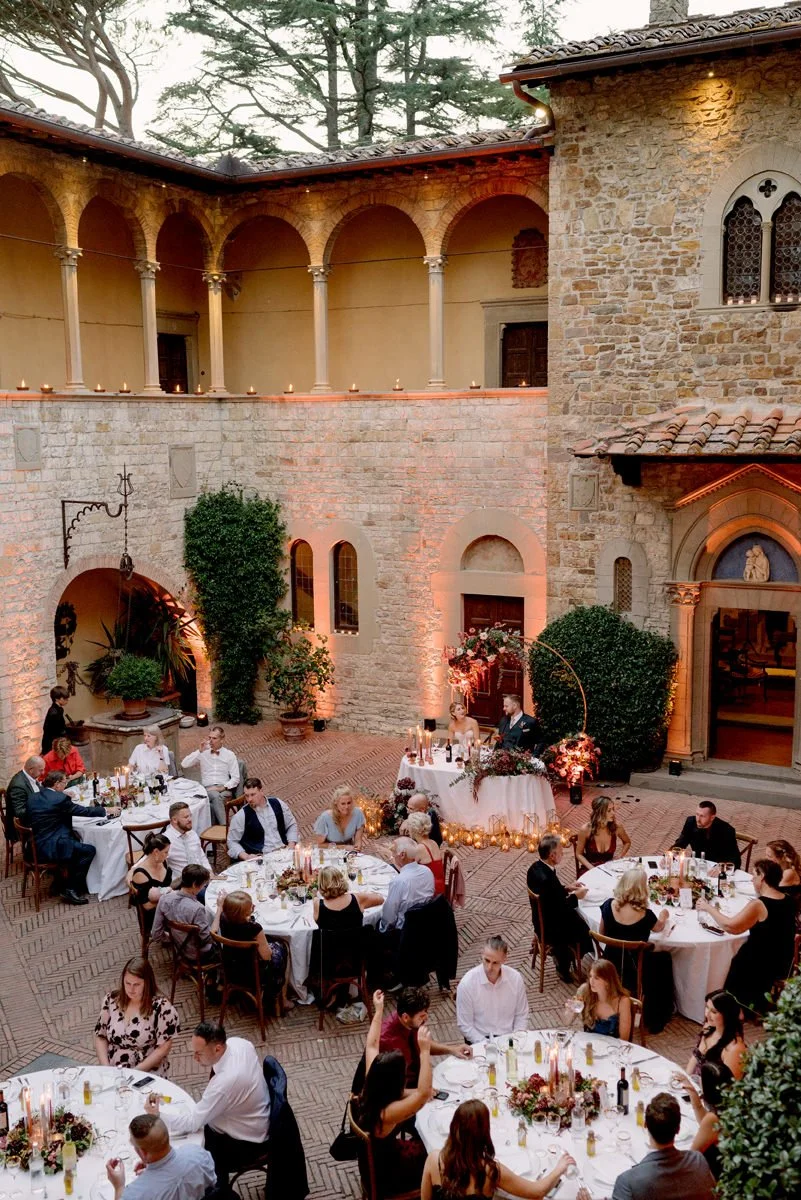 Wedding guests enjoying dinner together in the courtyard of Castello Il Palagio.