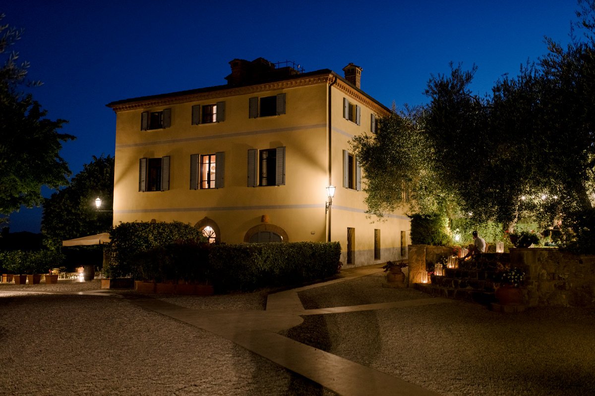 Terre di Nano wedding venue at night, with the main building softly lit and an outdoor wedding dinner nearby.
