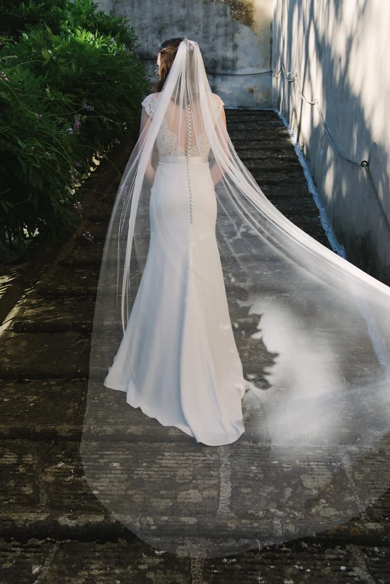 Bride standing on the courtyard stairs of Villa Medicea di Lilliano with veil flowing behind her