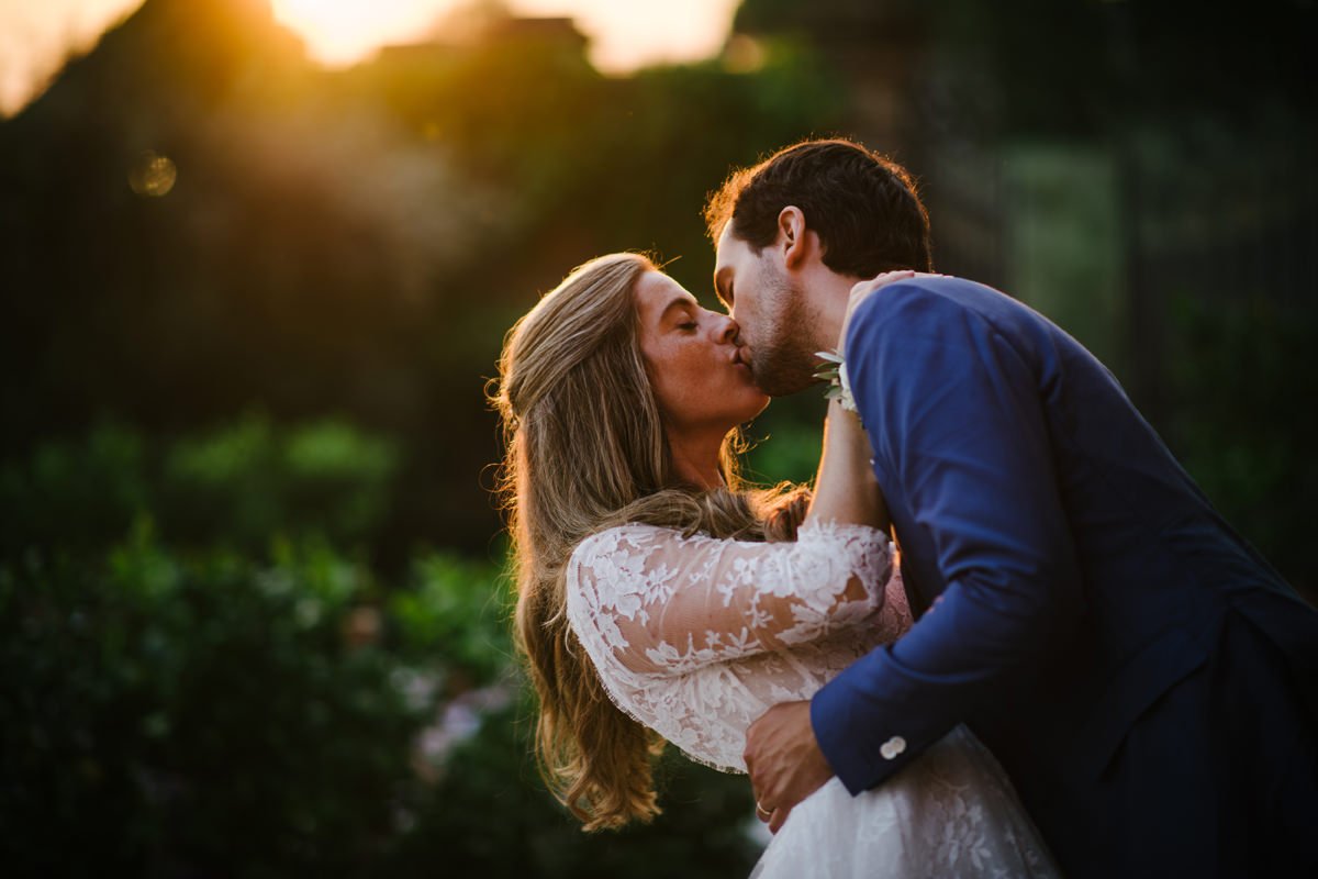 Wedding couple kissing in front of Villa Medicea di Lilliano during sunset