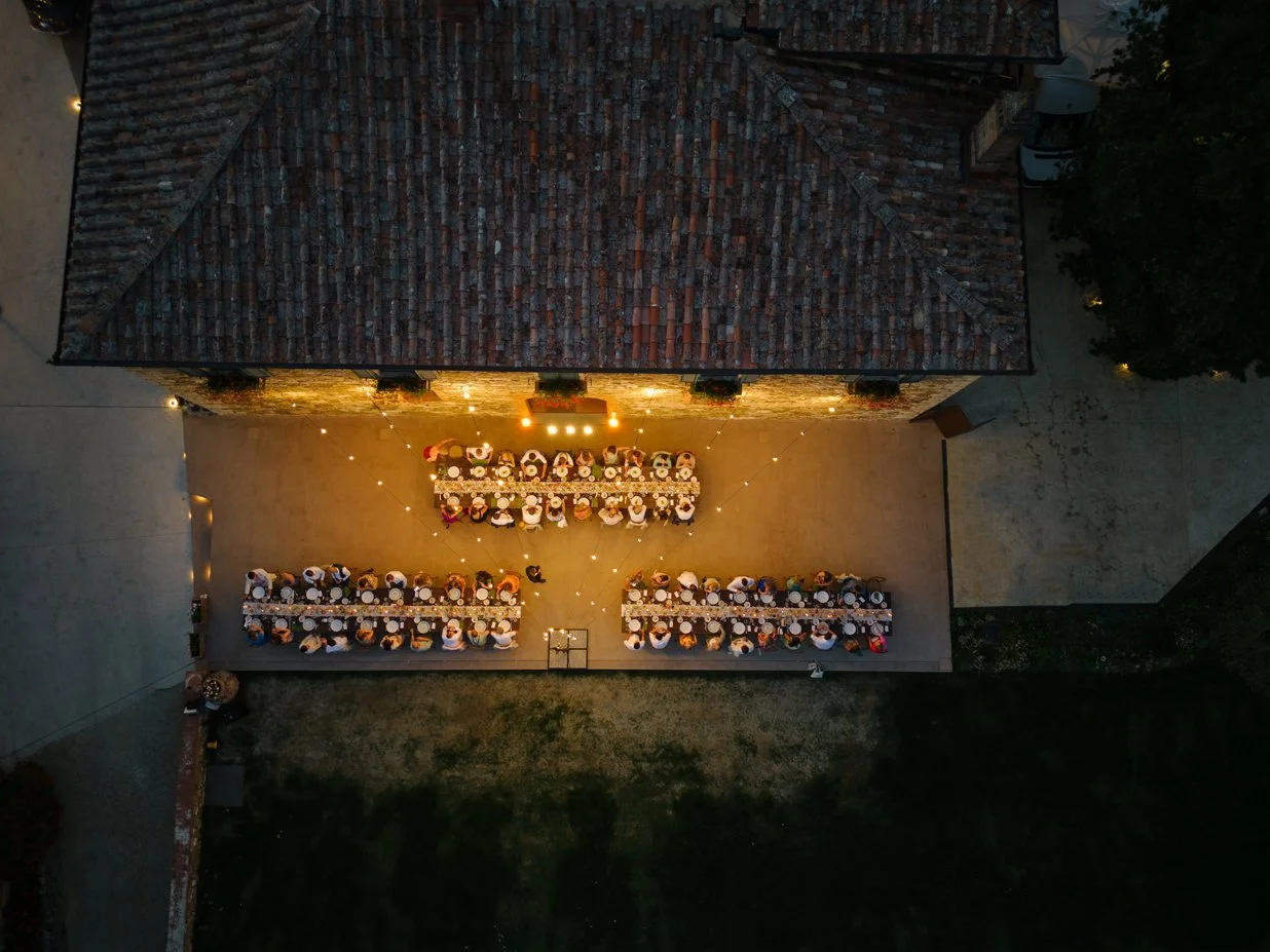 Drone view of three long wedding dinner tables set in front of the villa at Le Filigare wedding venue.