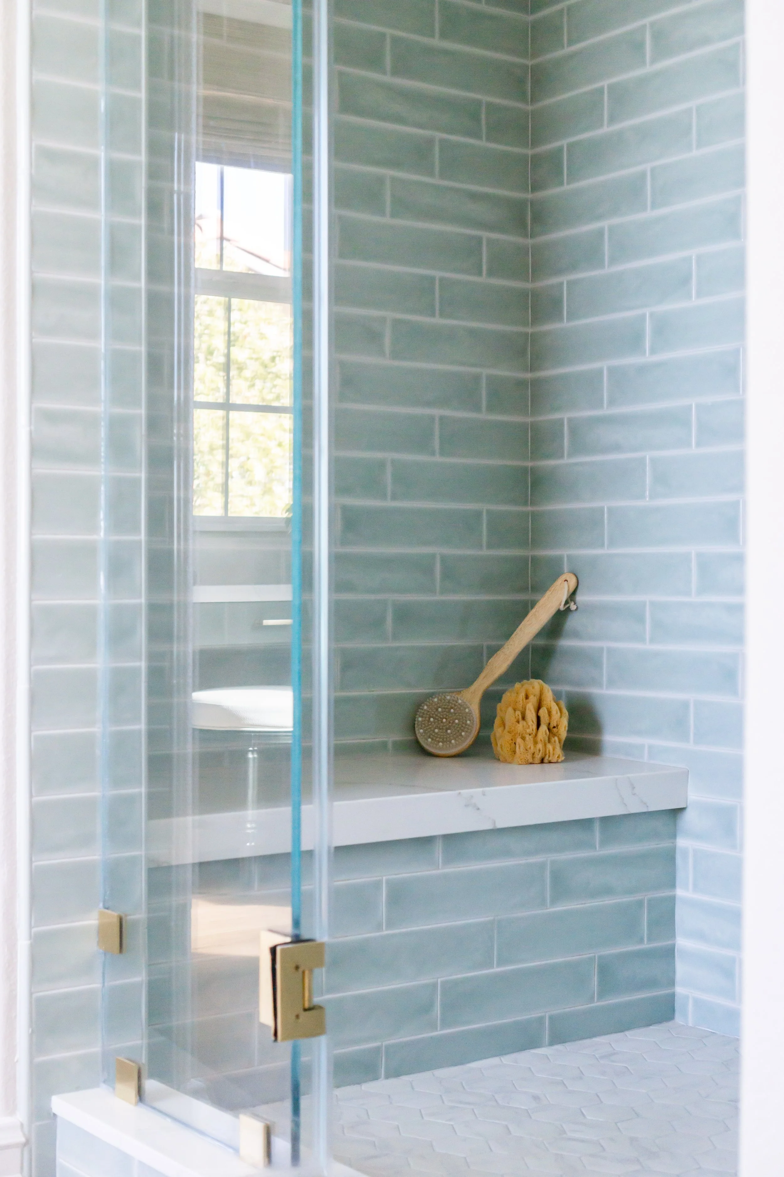 Custom walk-in shower with blue subway tile, frameless glass enclosure, recessed shower niche, and built-in bench in a luxury bathroom remodel in Yorba Linda, California by Apex Construction & Restoration Inc.