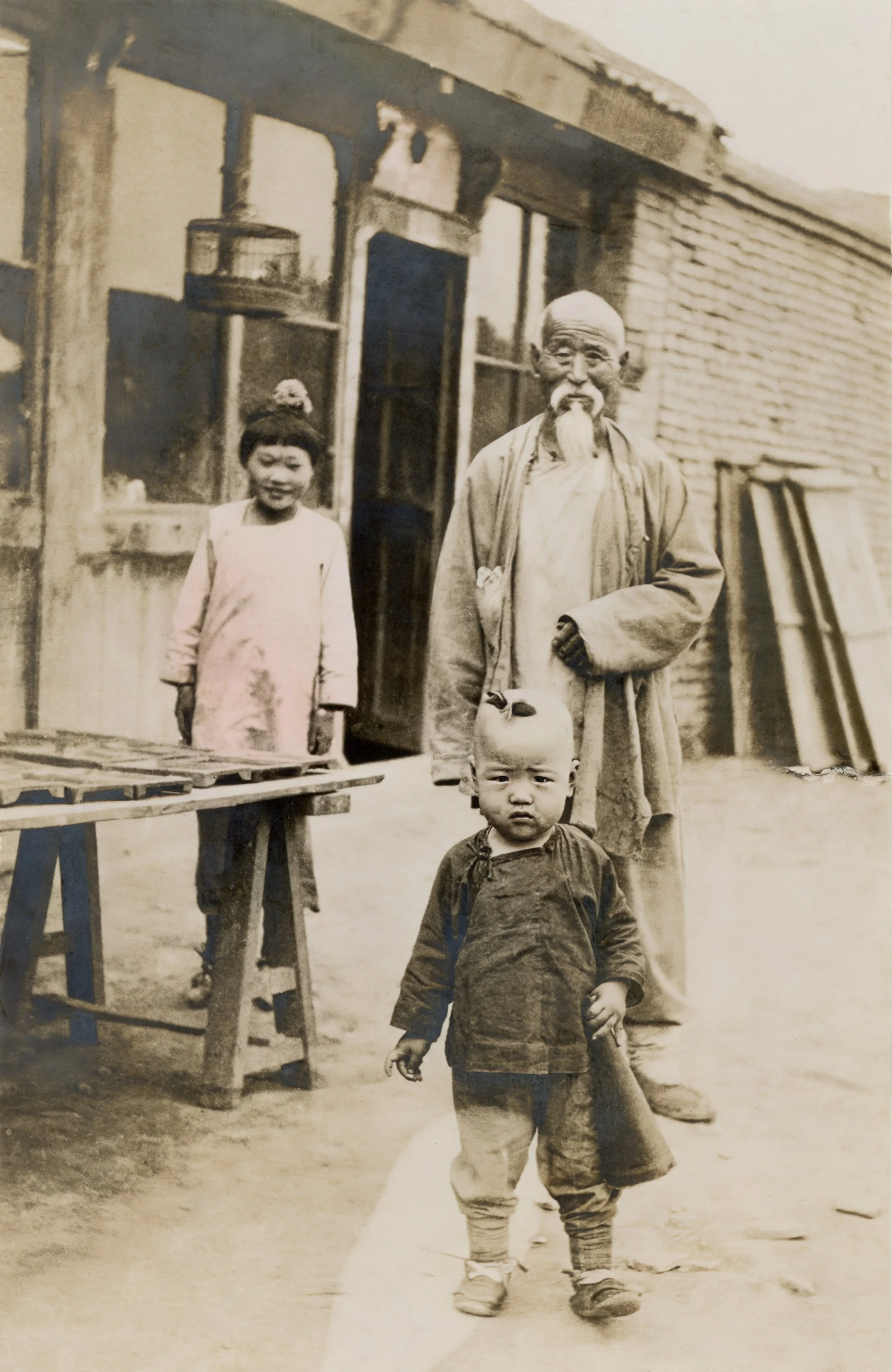 An elderly Chinese man with two young children. A scan from a colorized print.
