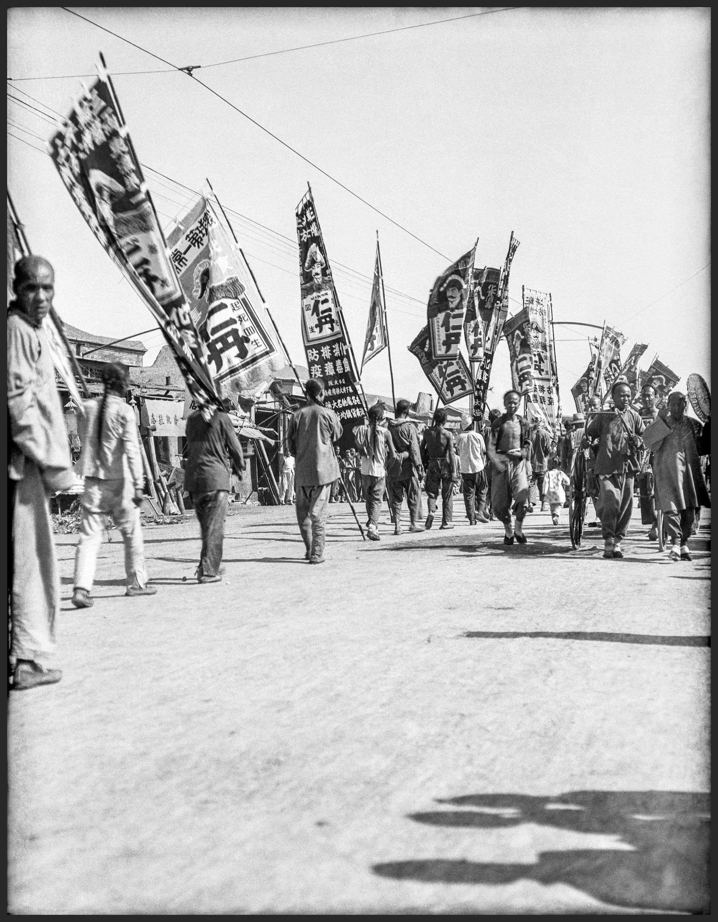 Chinese protesters hold flags and banners while walking the street.