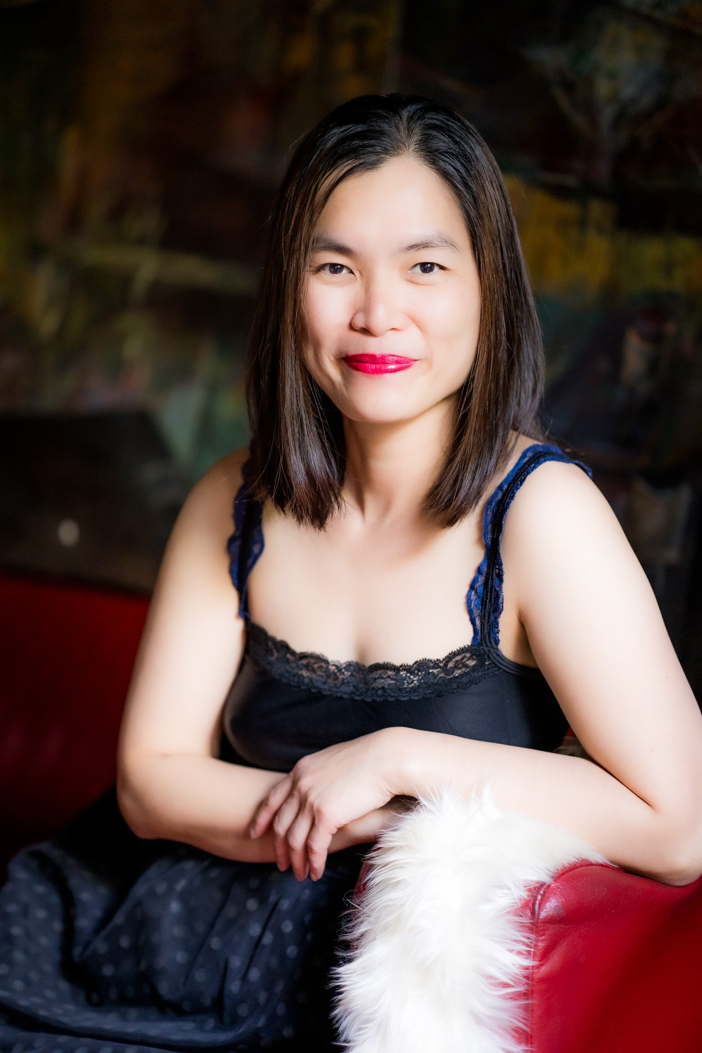 Woman sitting on a red sofa wearing a black dress