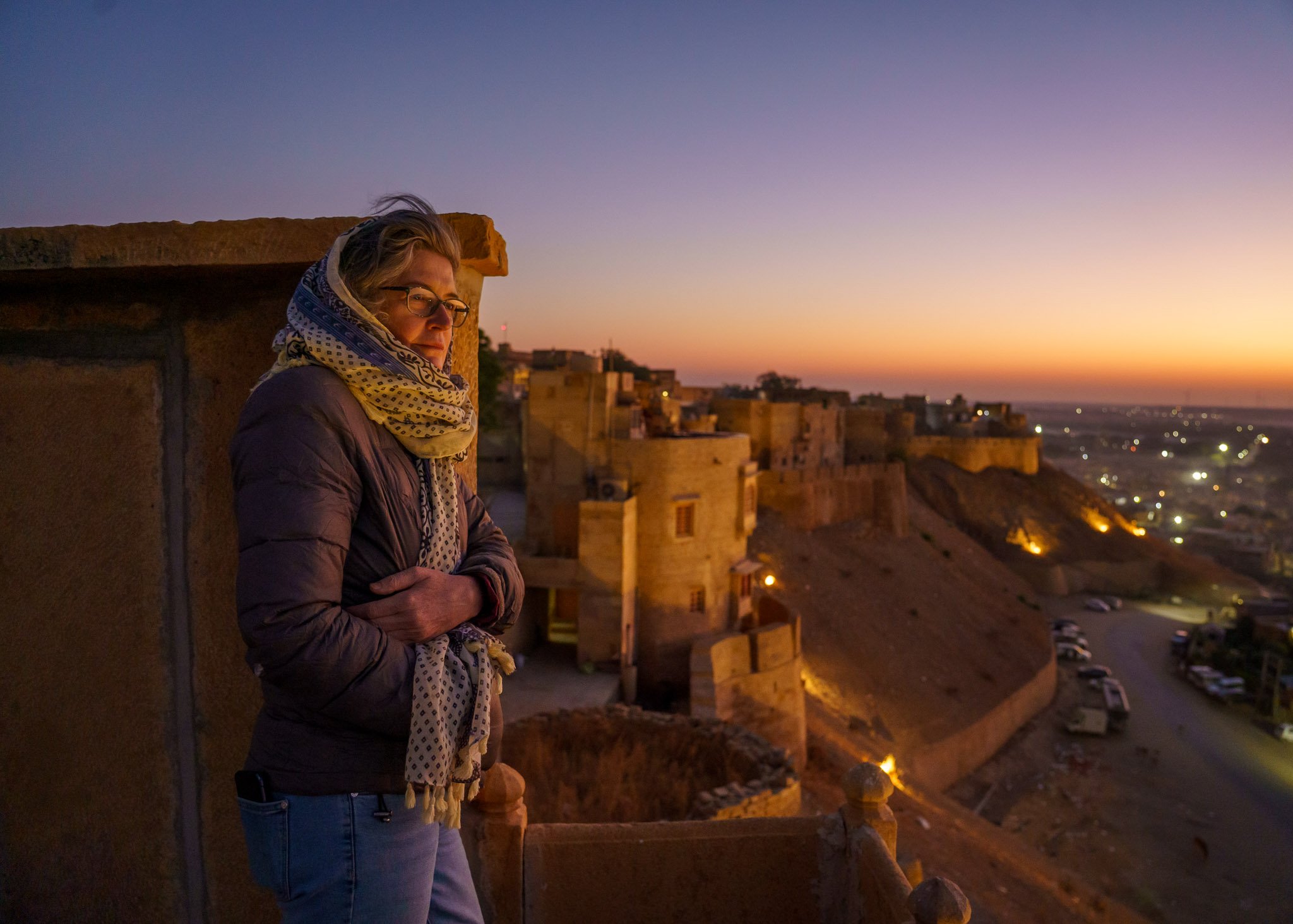 A woman on the rooftop of Jaisalmer Fort Rajasthan India looks out over the Thar Desert at dawn