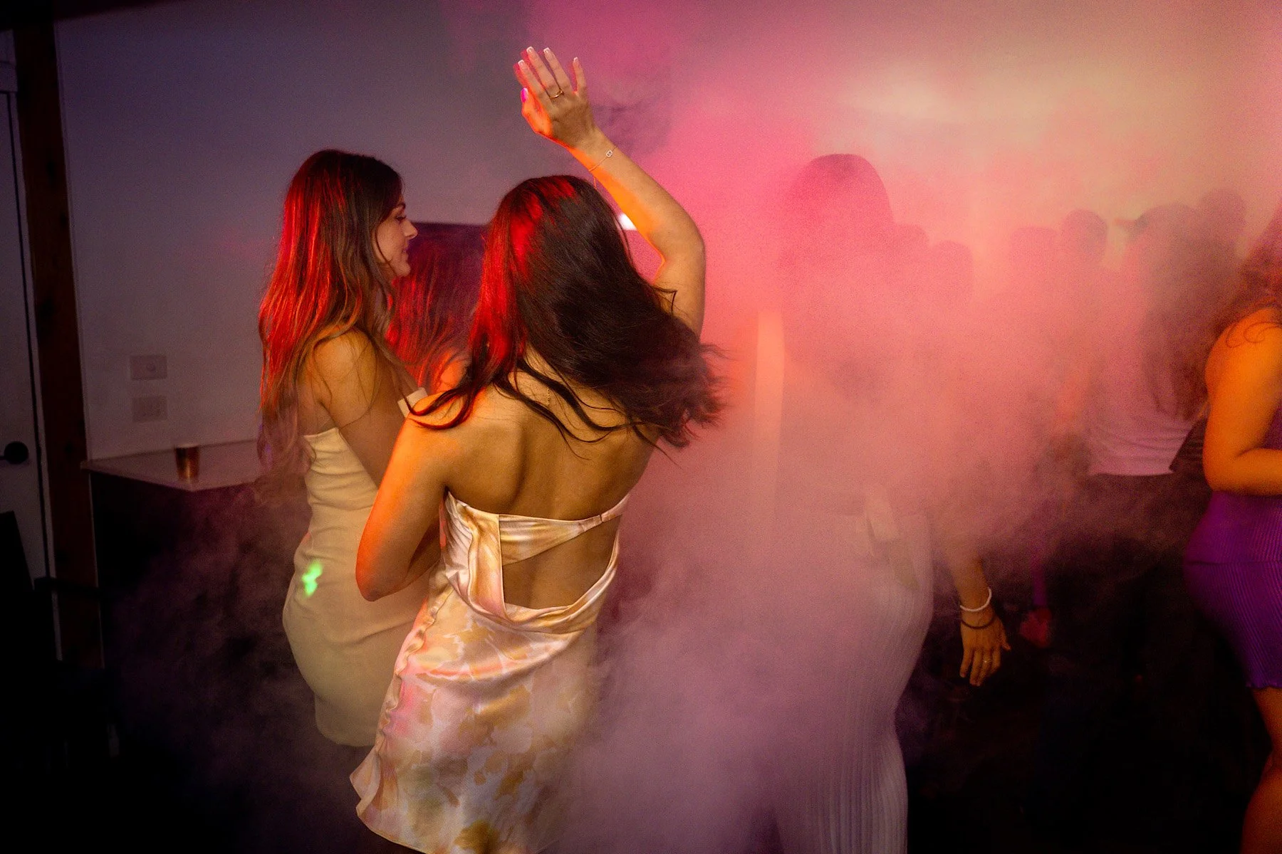 Young women at a party dance the night away surrounded by coloured swirls of smoke