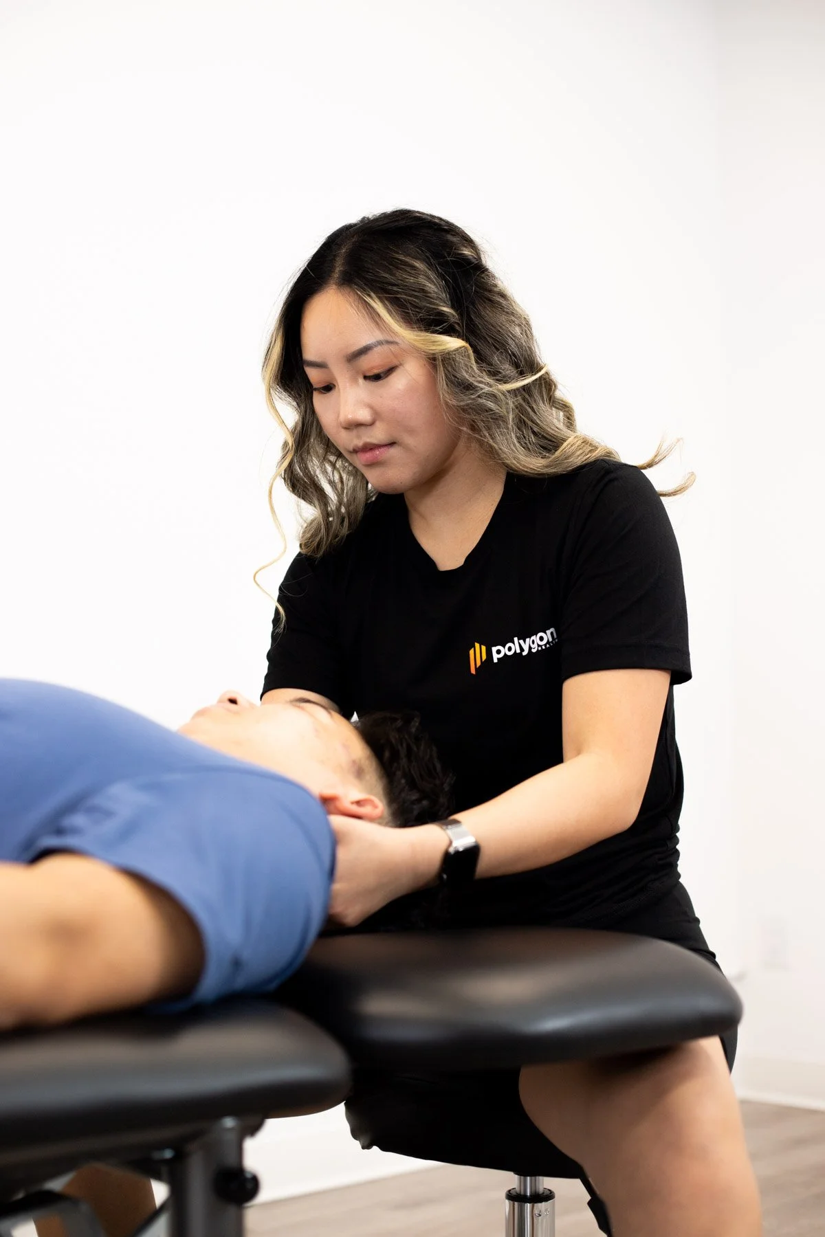 Physical therapist assisting a patient with leg exercises on a pilates reformer machine