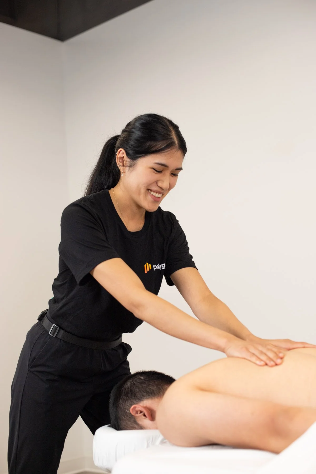 A woman gives a massage to a man lying face down on a massage table in a spa or therapy room.