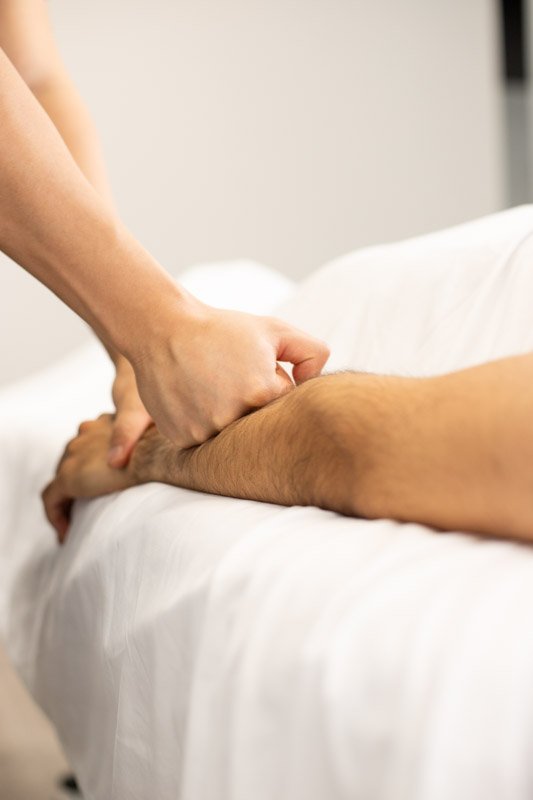 Physical therapist assisting a patient with leg exercises on a pilates reformer machine
