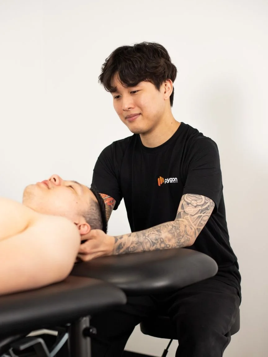 Physical therapist assisting a patient with leg exercises on a pilates reformer machine