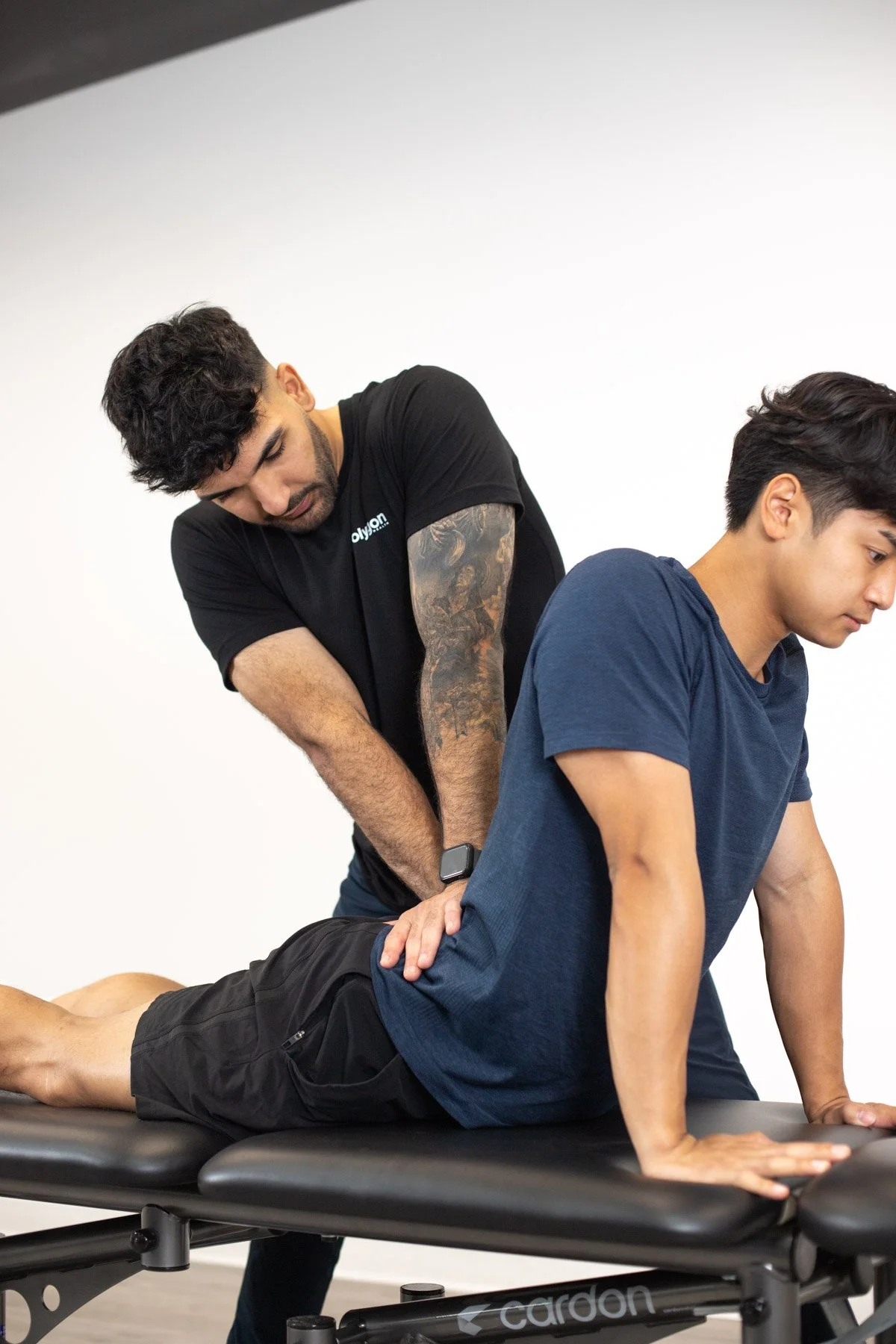 A chiropractor adjusting a patient's back on a treatment table in a clinic.