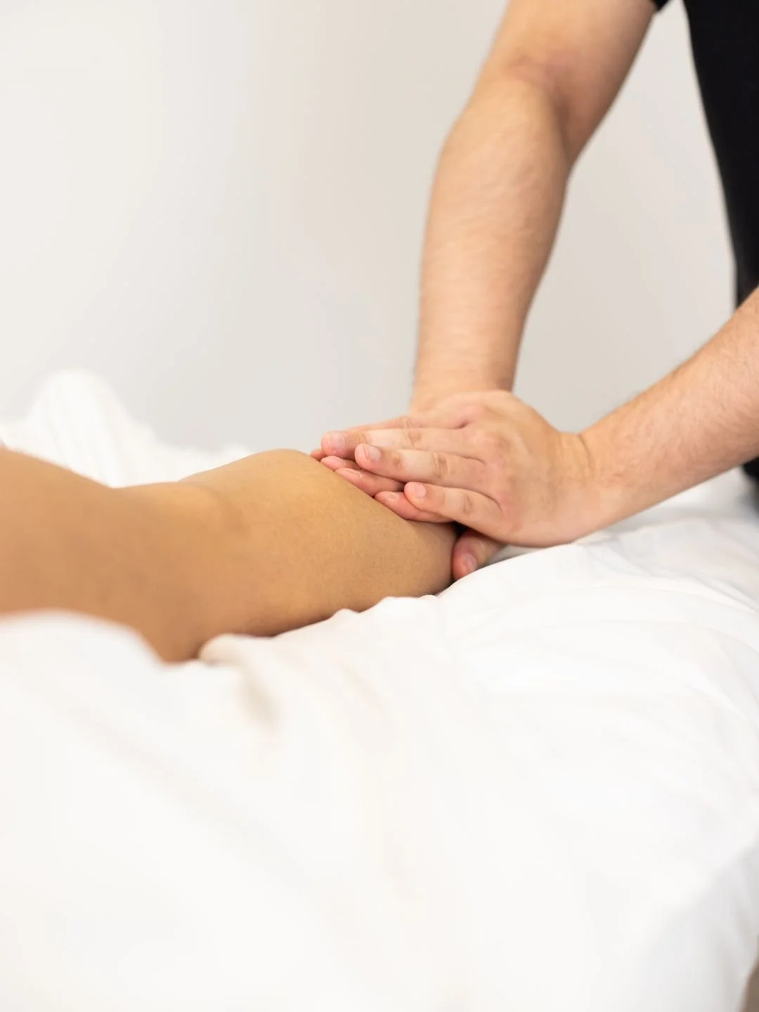 Physical therapist assisting a patient with leg exercises on a pilates reformer machine