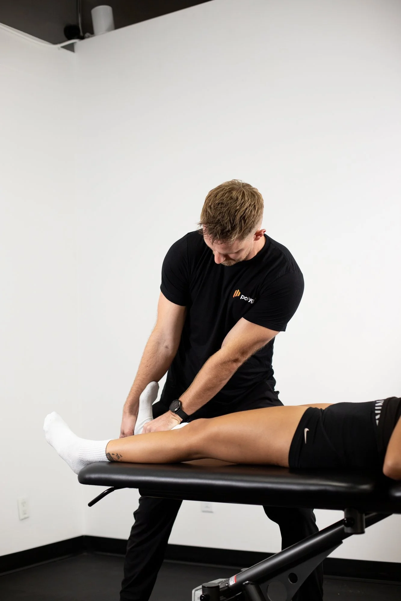 Physiotherapist Connor Fraser doing hands-on ankle treatment at Polygon Health in Burnaby
