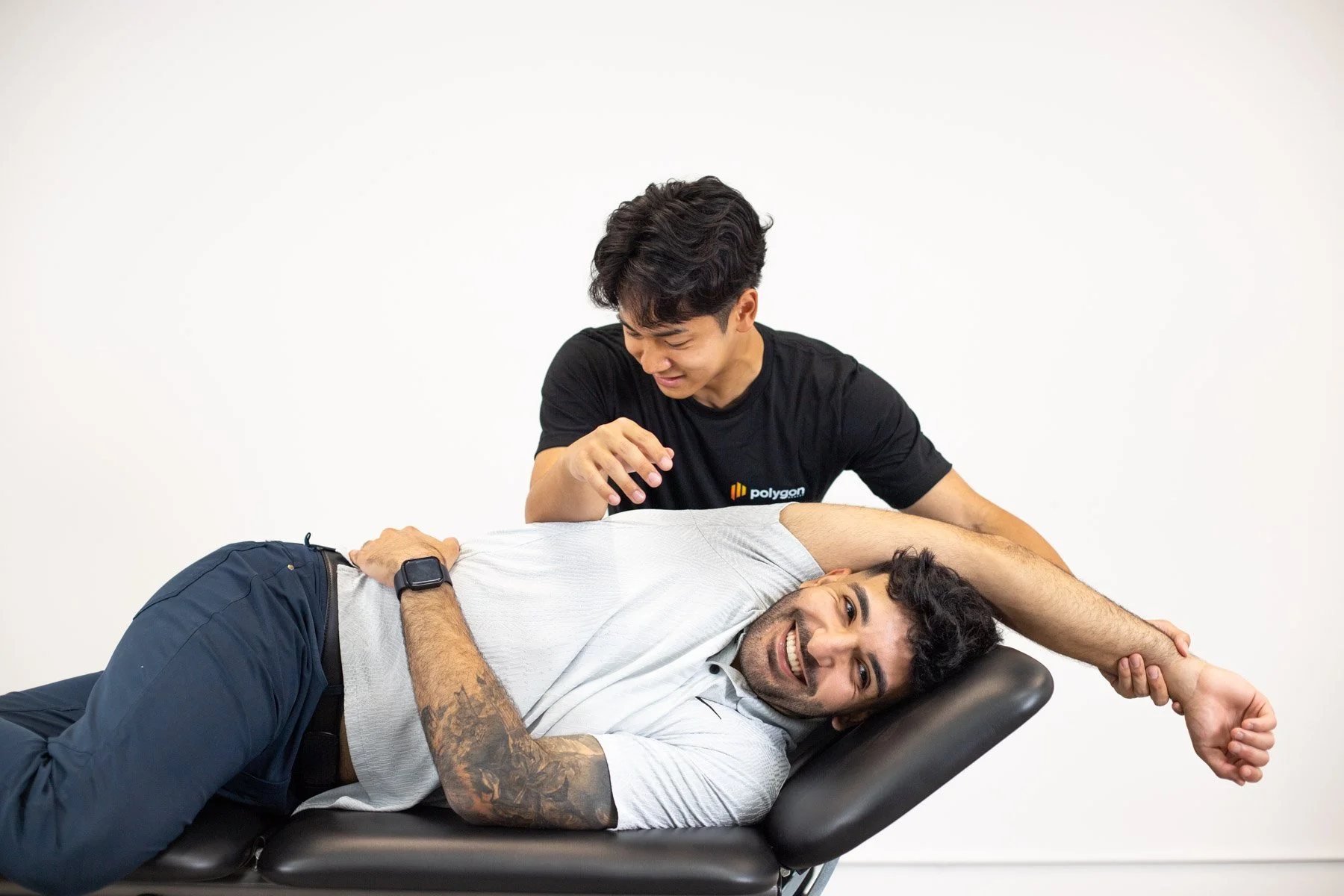 Physical therapist assisting a patient with leg exercises on a pilates reformer machine