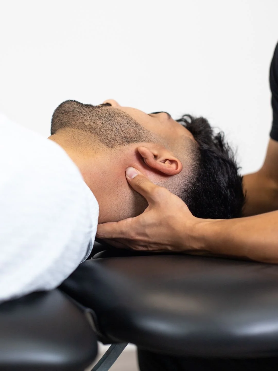 A woman providing neck therapy to a man lying on a chiropractic table.