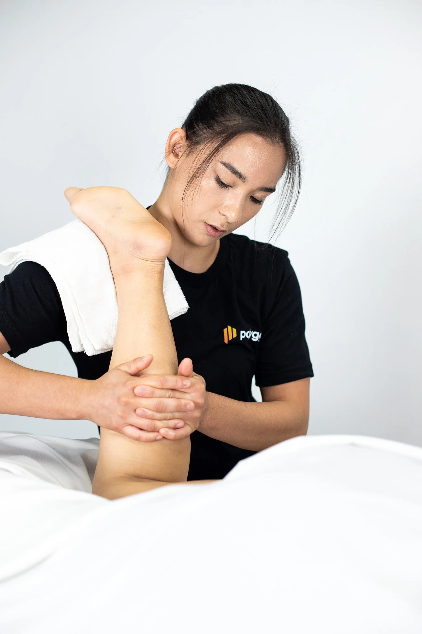 Physical therapist assisting a patient with leg exercises on a pilates reformer machine