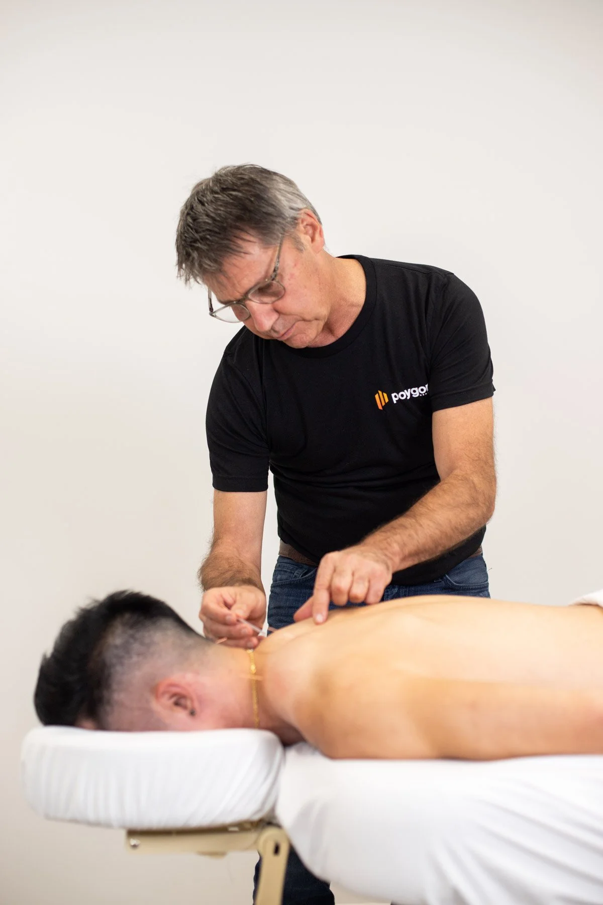 A man receiving acupuncture treatment from an acupuncturist in a clinic setting.