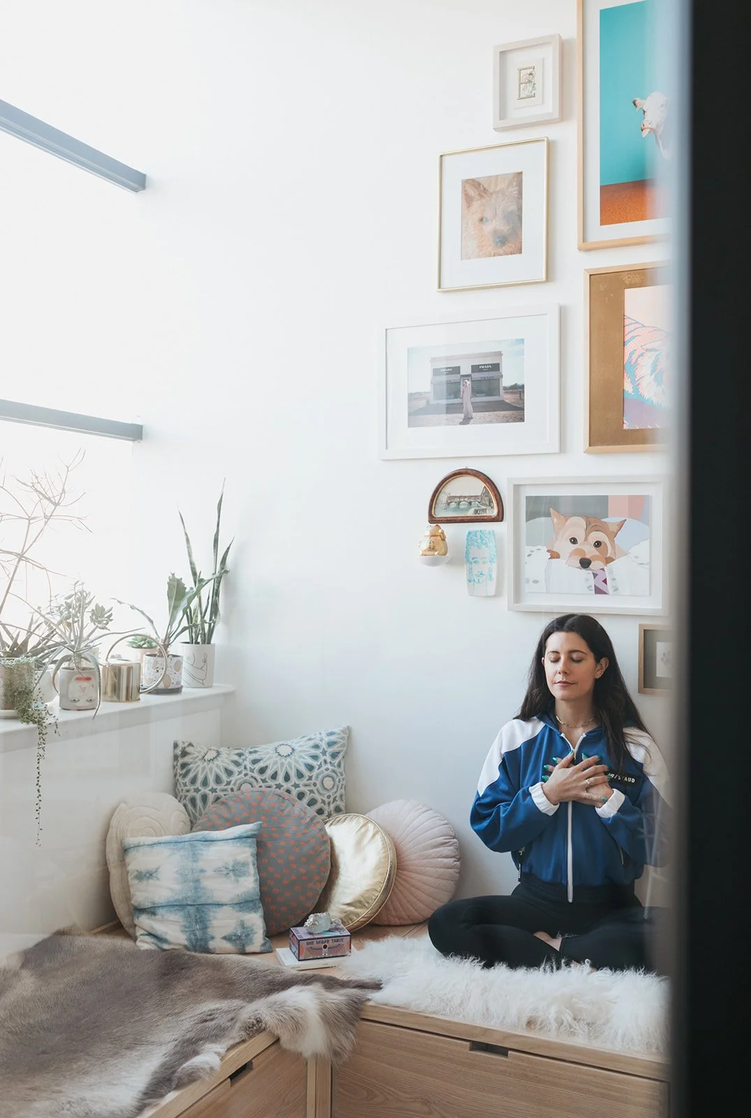 Jena Burton, Women’s Health Coach, sitting cross-legged with her eyes closed in a cozy room.