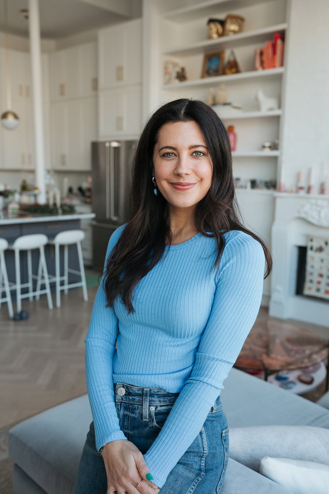 Jena Burton, National Board-Certified Health & Wellness Coach, smiling in a blue sweater at home.
