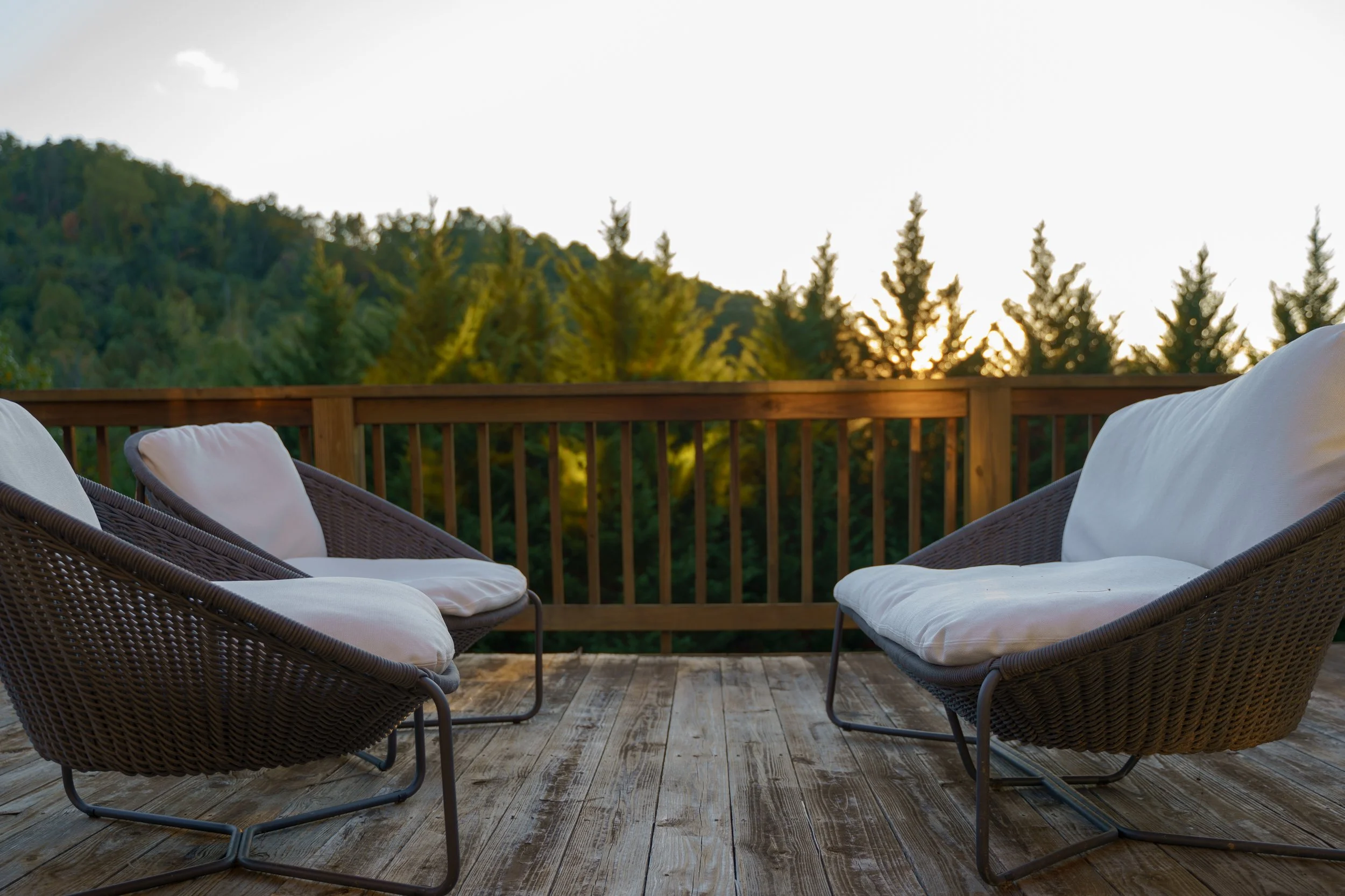 Outdoor furniture on a deck overlooking the valley and sunset.