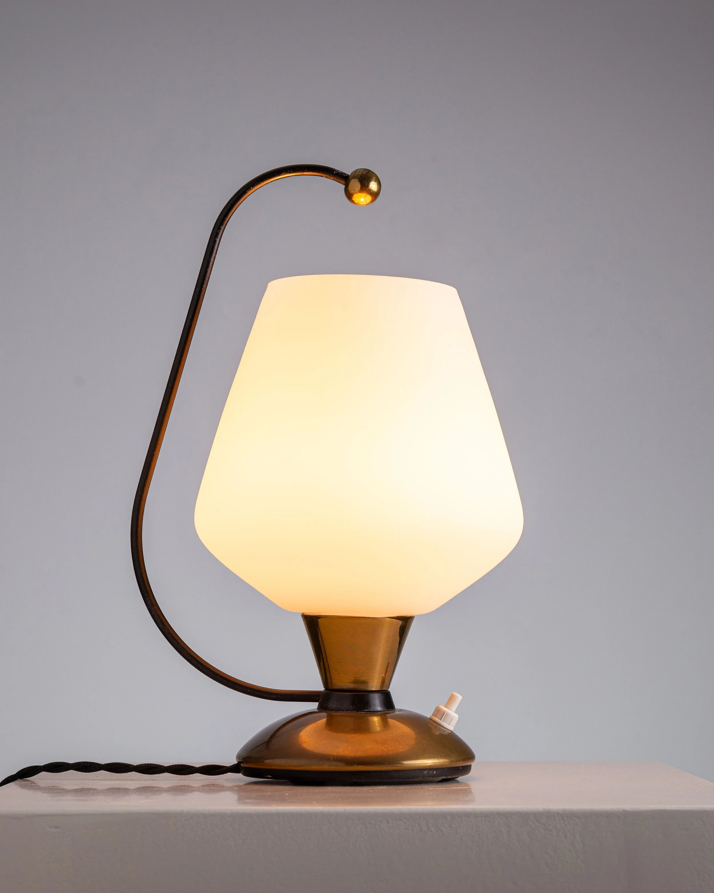 Brass table lamp with curved stem and opaline glass shade