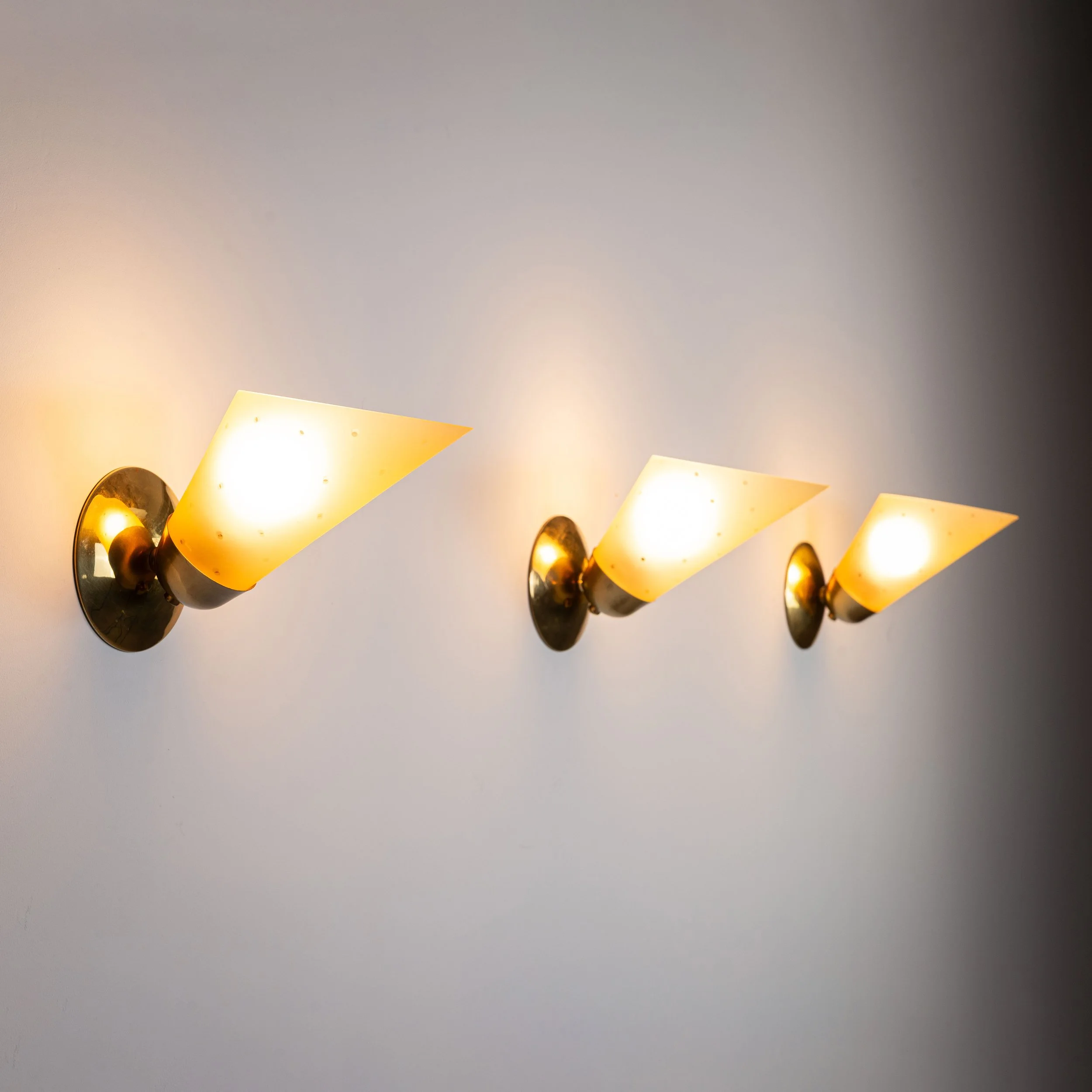 Set of three brass sconces with decorated yellow glass shades
