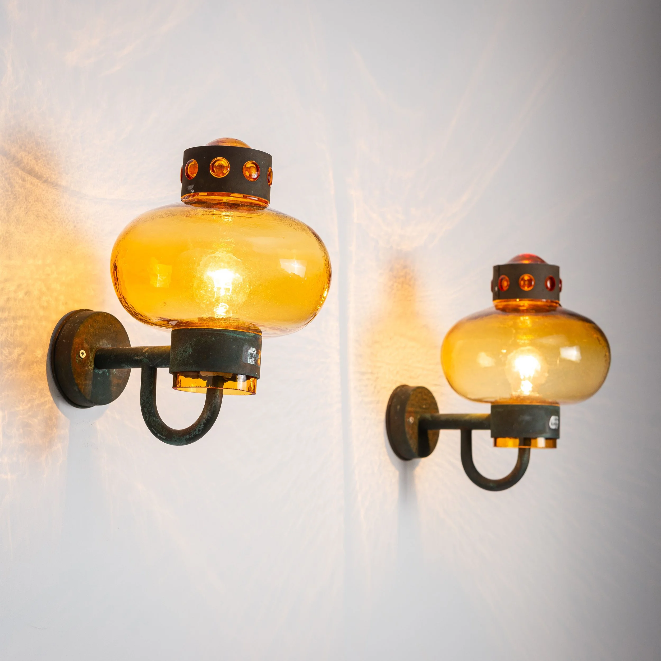Pair of brass wall lamps with decorated amber coloured shades