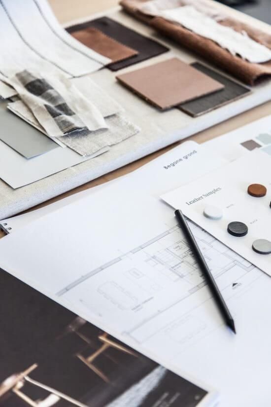 Interior design palette with fabric swatches, color samples, and architectural plans on a workspace table.