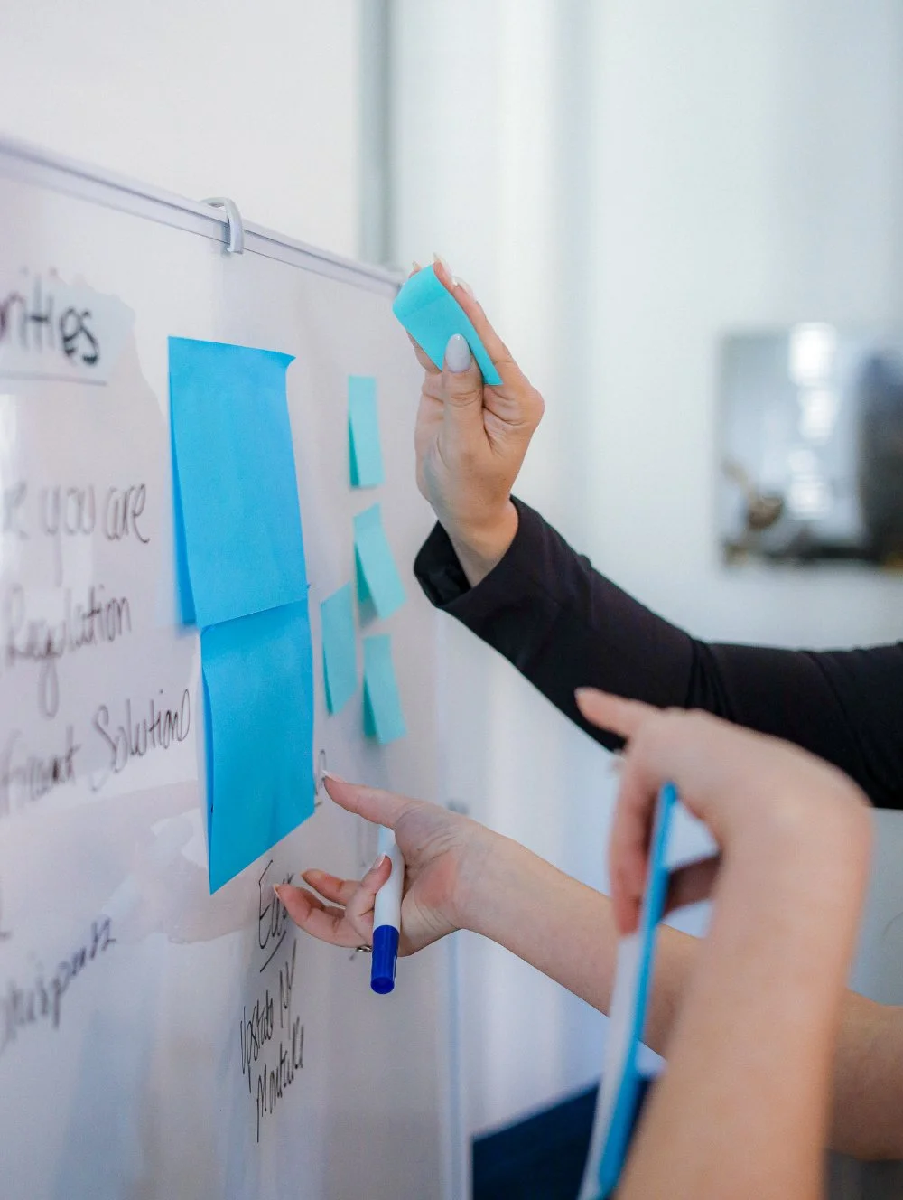 Hands place sticky notes on a whiteboard, mapping ideas and strategy. A behind-the-scenes look at planning thoughtful systems that support clear, intentional marketing.