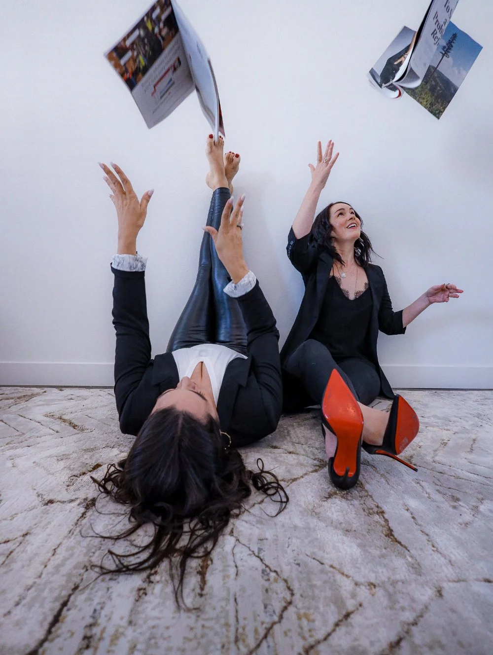 Two women tossing papers in the air, expressing frustration and overwhelm with low sales and business challenges.