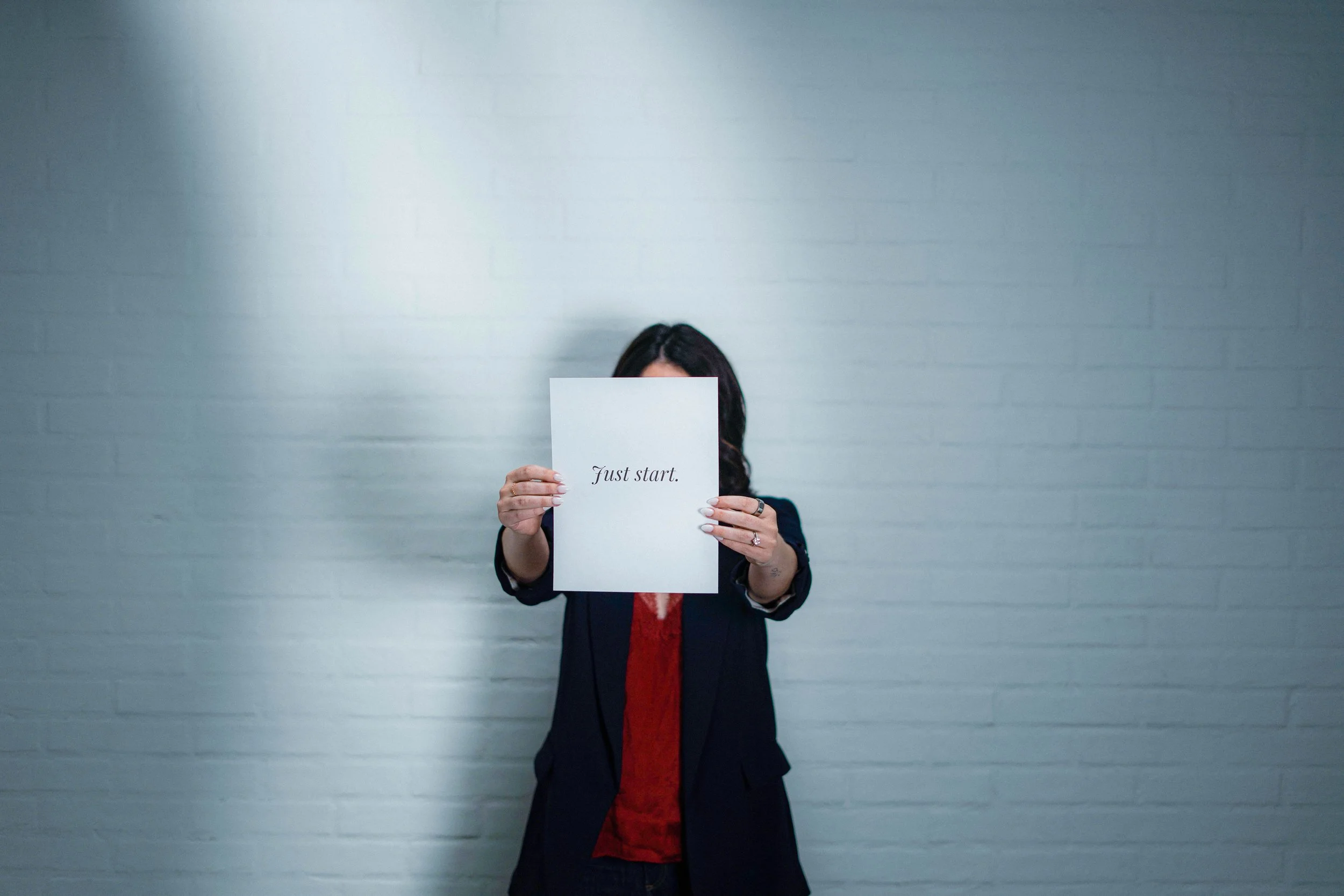 Chelsea Quint holding a sign that says 'just start,' because knowing how to write a sales page that converts is step one, starting is step two.