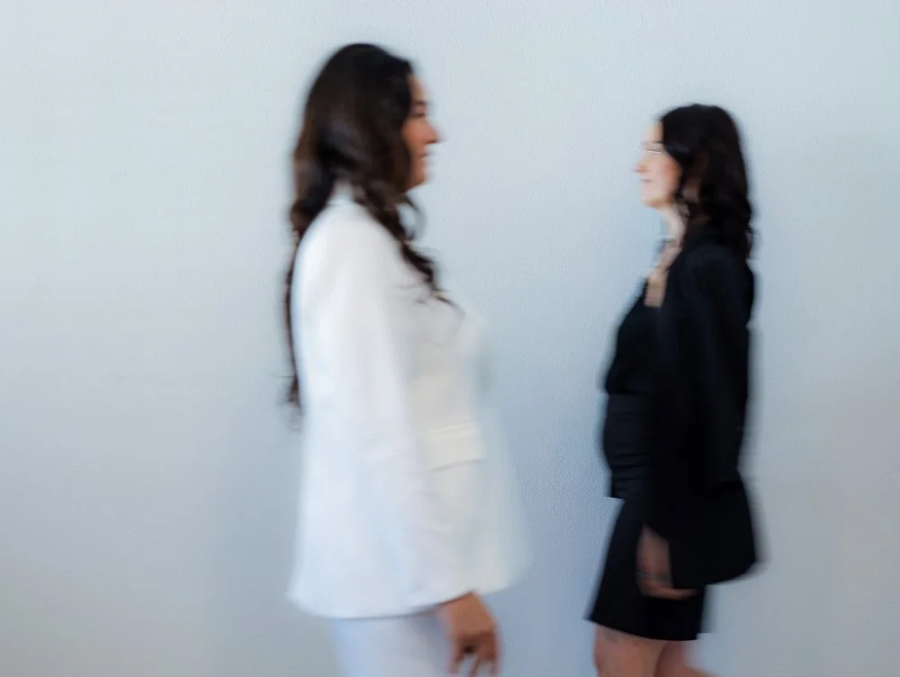 Two women walking toward each other in a minimalist space, slightly blurred in motion. Visual metaphor for shifting perspectives, collaboration, and the evolving process behind clear, human sales messaging.
