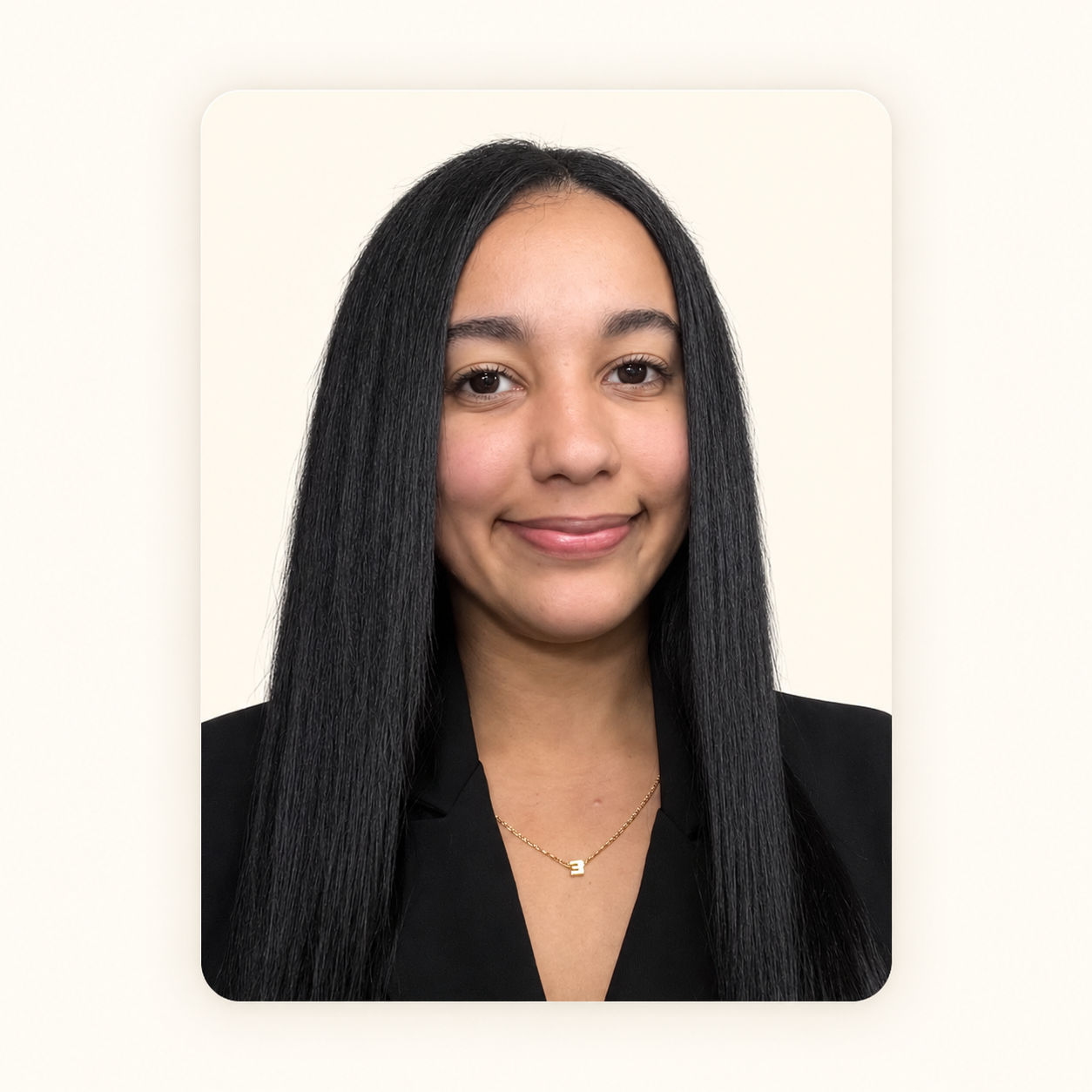 A young woman with long black hair, wearing a black blazer and a gold necklace, smiling against a plain light background.